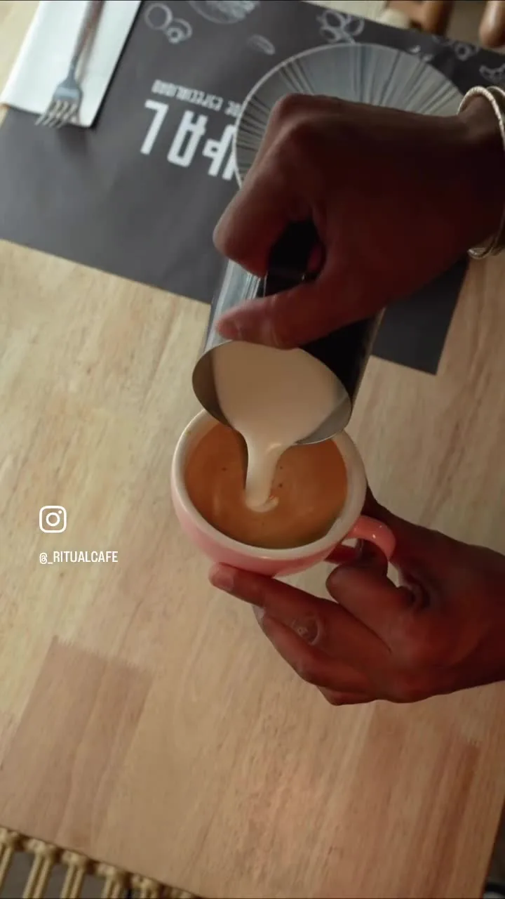 Las manos del barista dibujando latte art